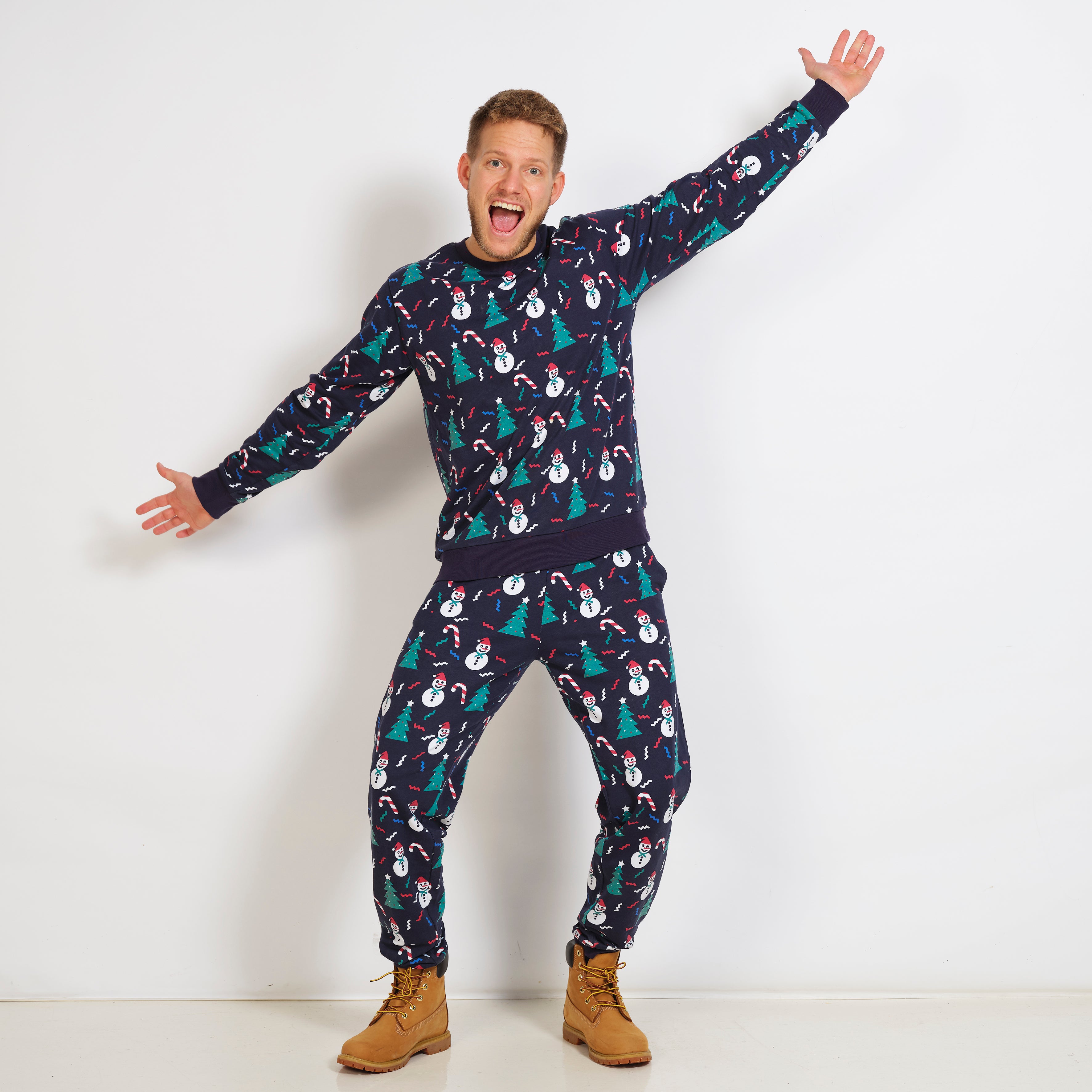 En glad mand med hænderne ud til siden er iført en blå julesweatsuit.