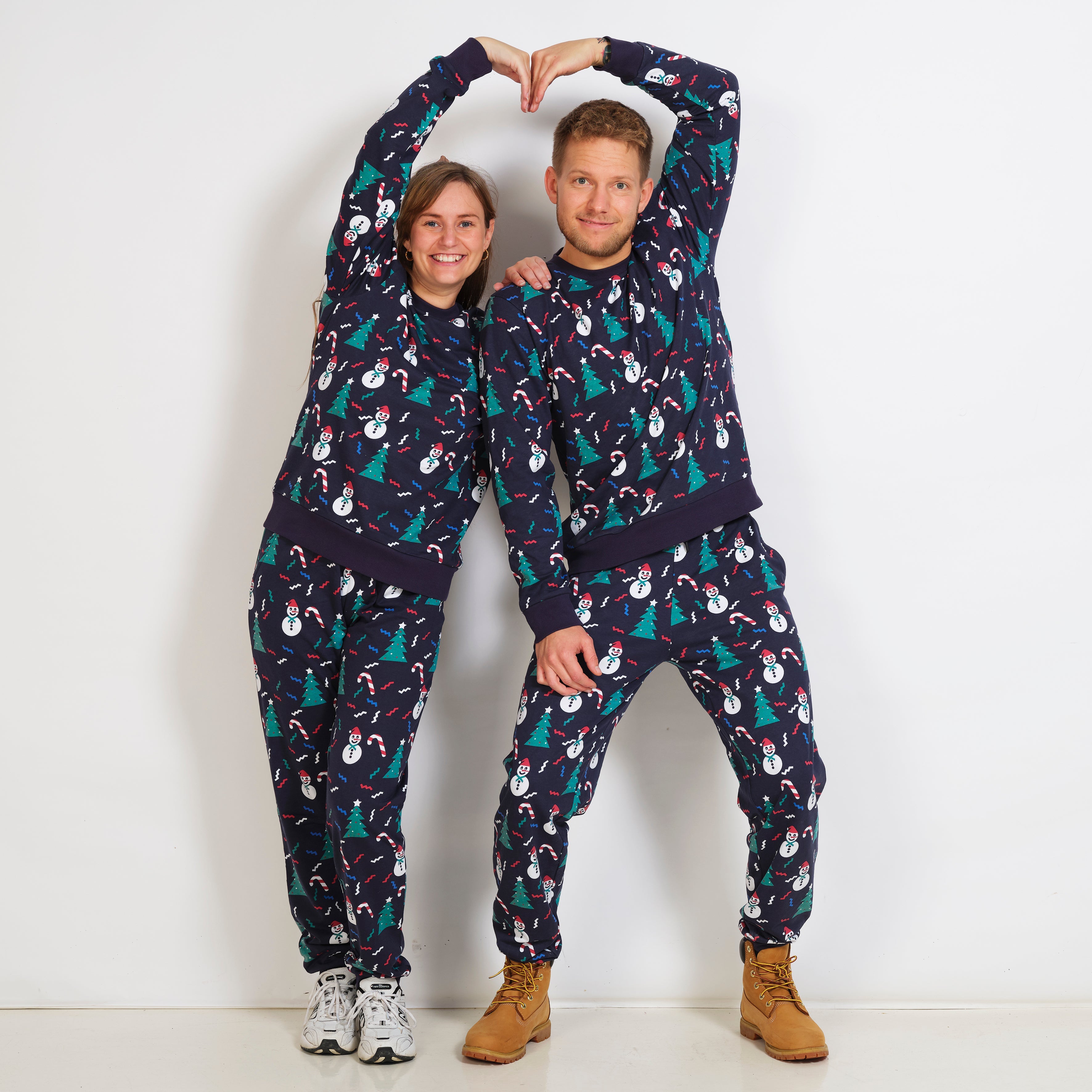 En mand og en dame poserer sammen i hver deres blå julesweatsuit.