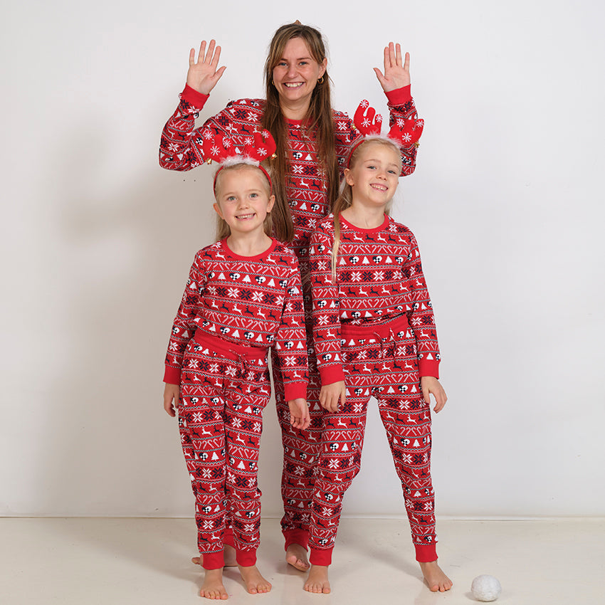 En dame og to børn iført hver deres røde sæt julepyjamas.