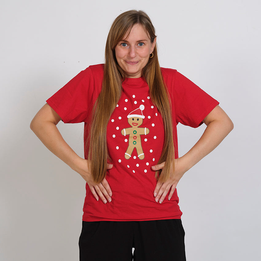 En dame poserer i hendes røde jule T-shirt med en kagemand på.