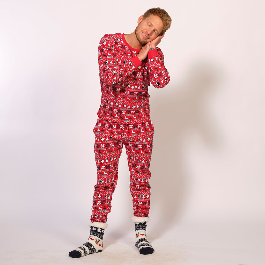 En afslappet mand i et par røde pyjamas med julemønster på.