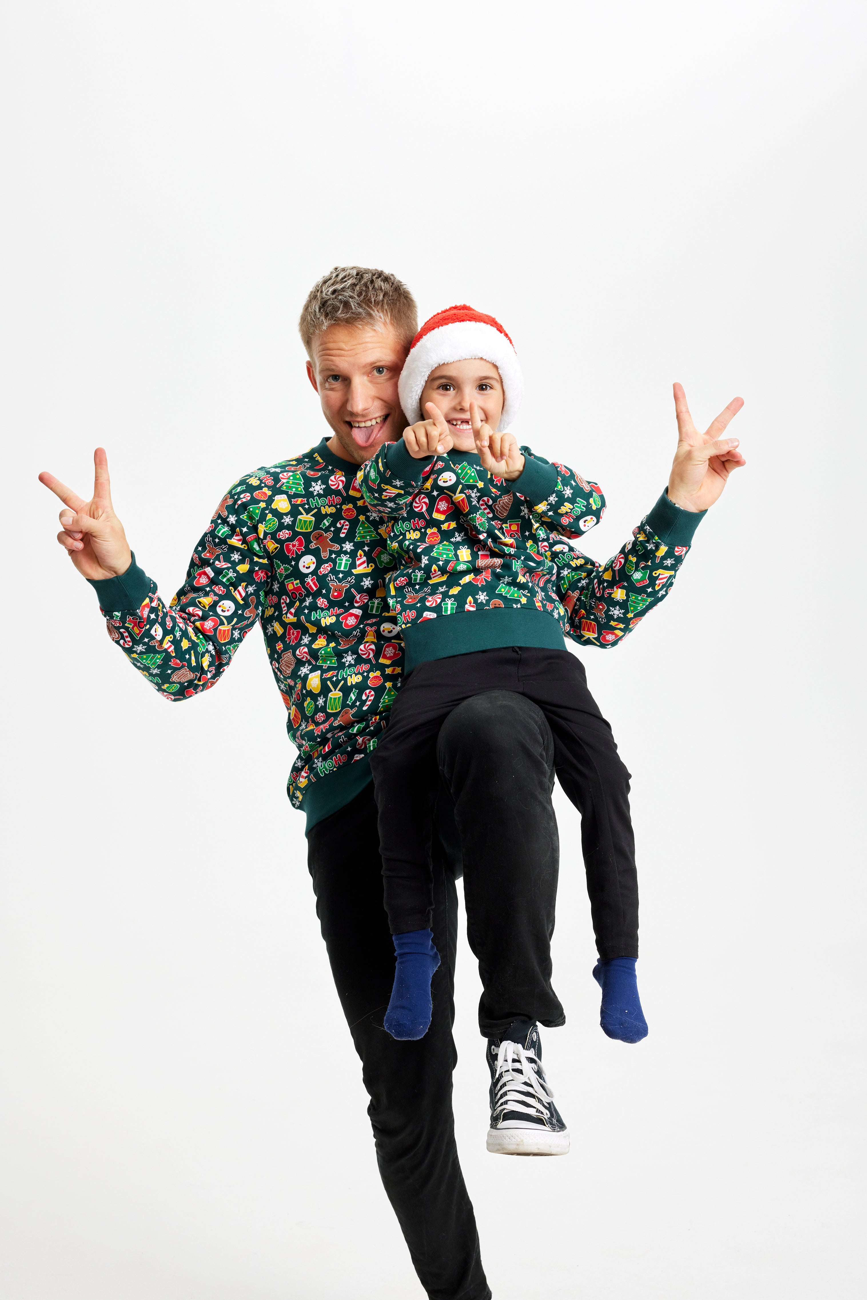Et barn og en mand iført grønne julesweatre med julemønster.