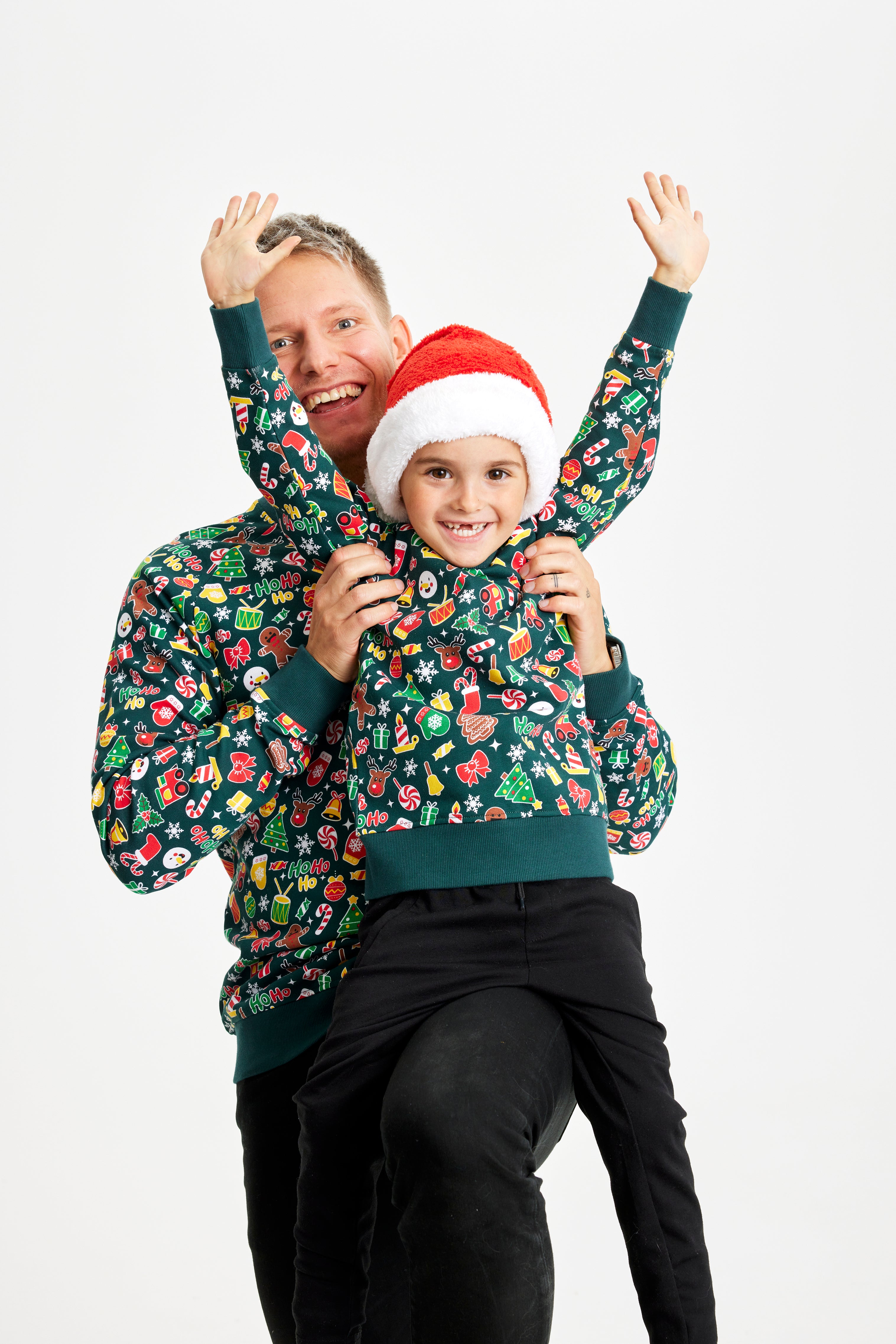 En mand og et barn poserer sammen iført grønne julesweatre med mønster.