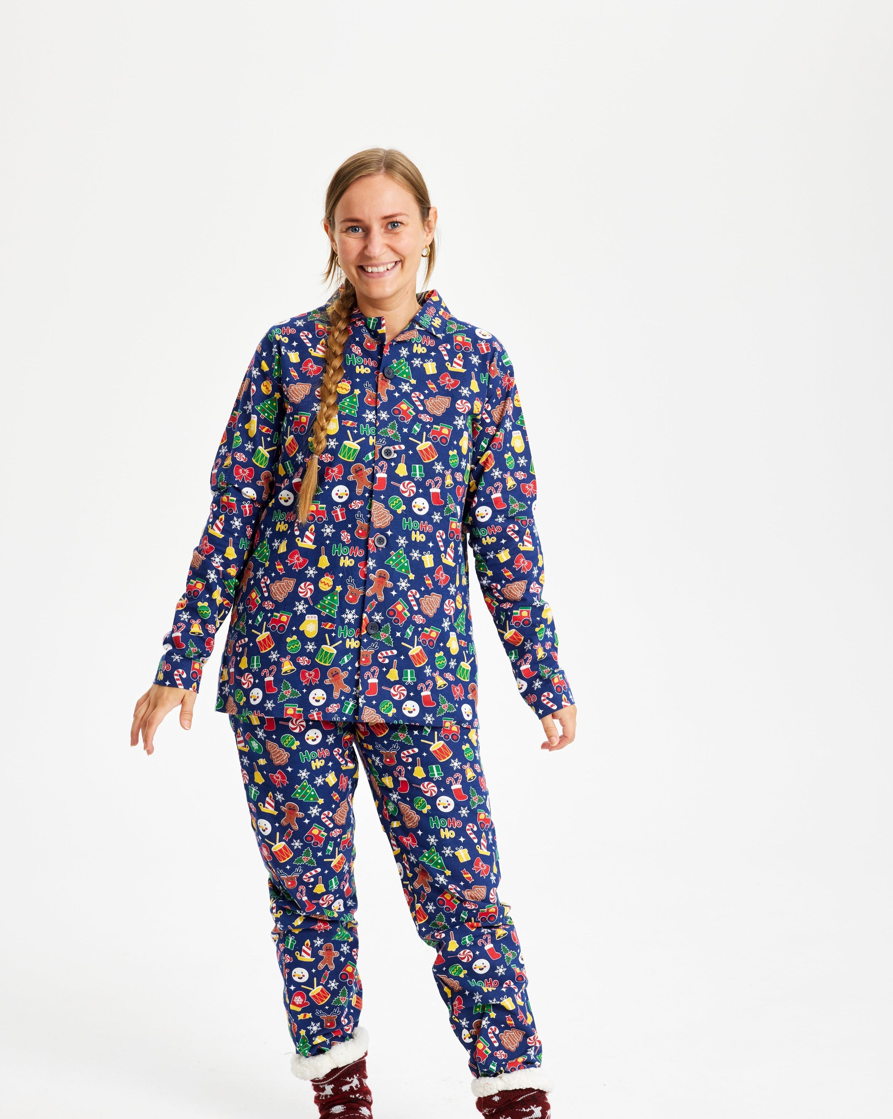 En dame med en fletning iført en julepyjamas med alverdens julepynt på.