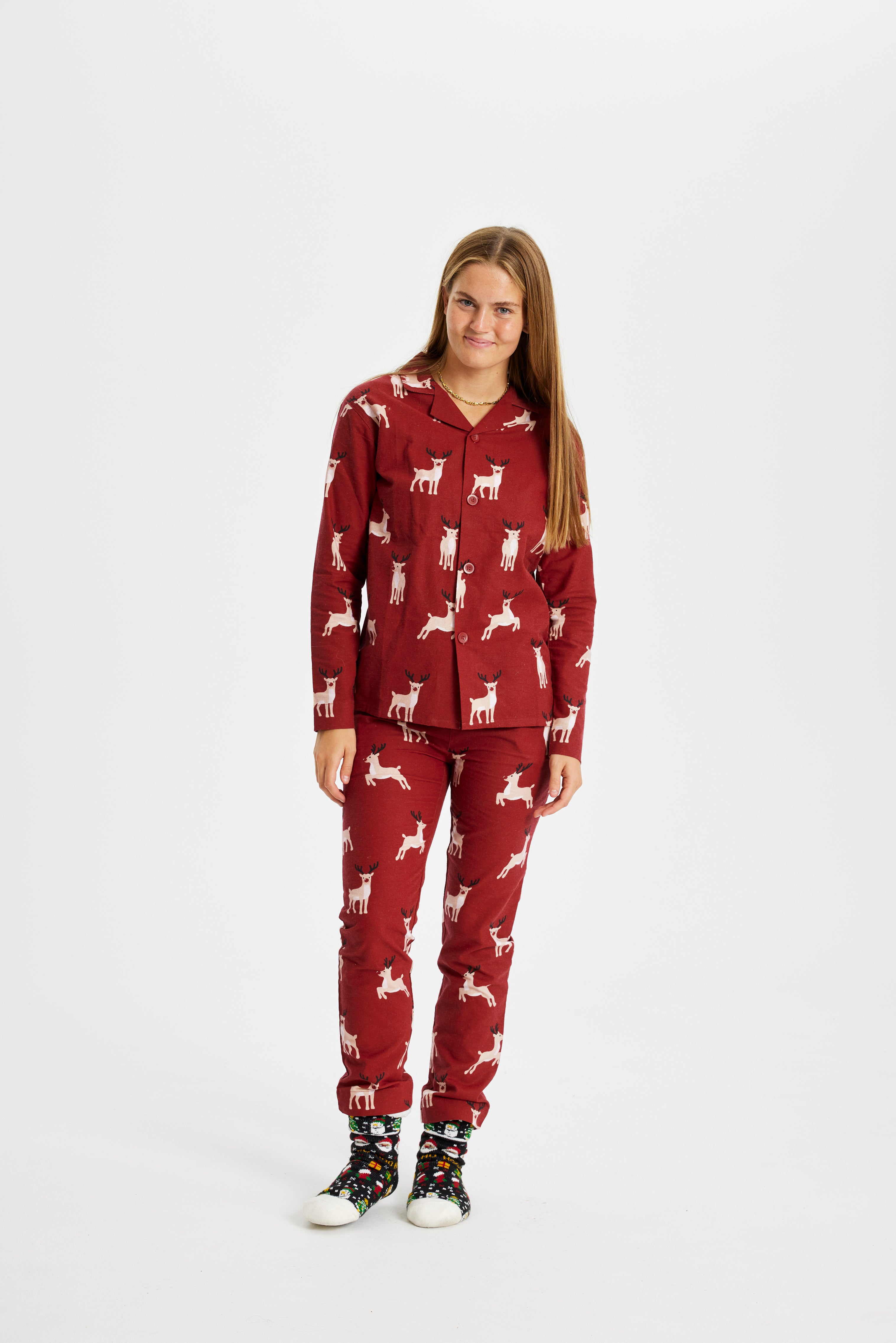 En smilende kvinde iført et pyjamassæt med rensdyr.