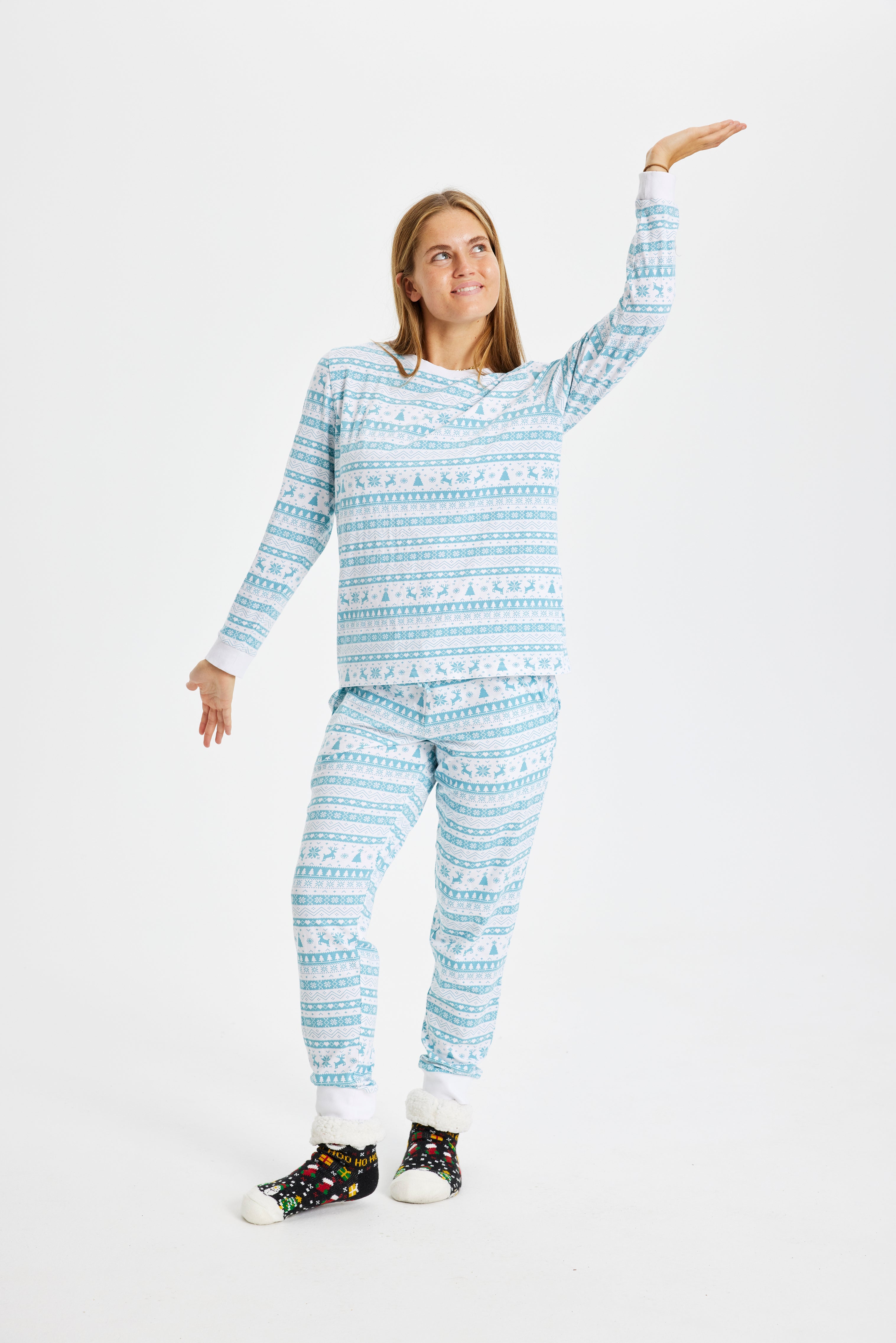 Glad dame har en sød julepyjamas på i blå og hvid med små juletræer og rensdyr.