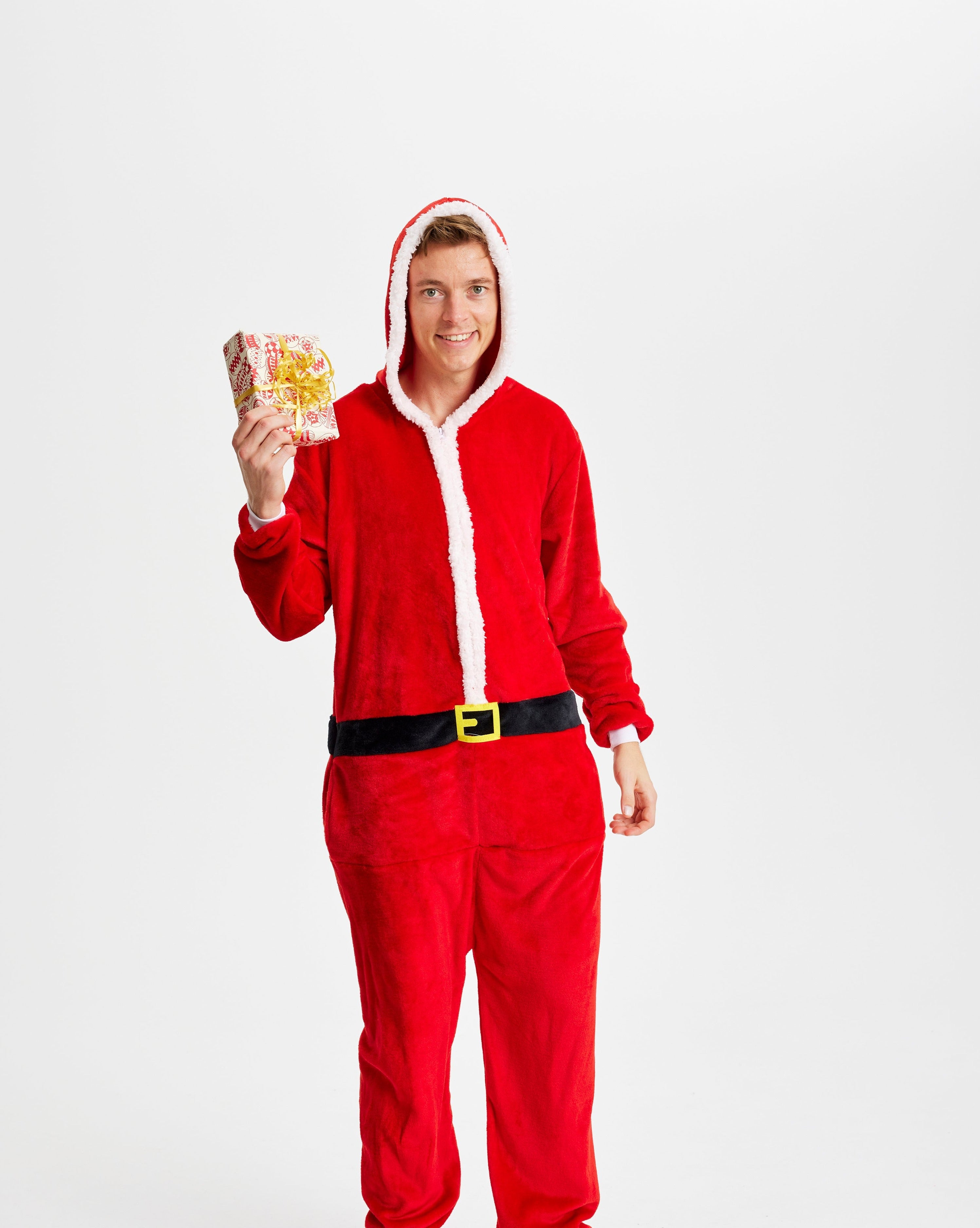En mand med en gave i hånde iført en jumpsuit inspireret af julemanden.