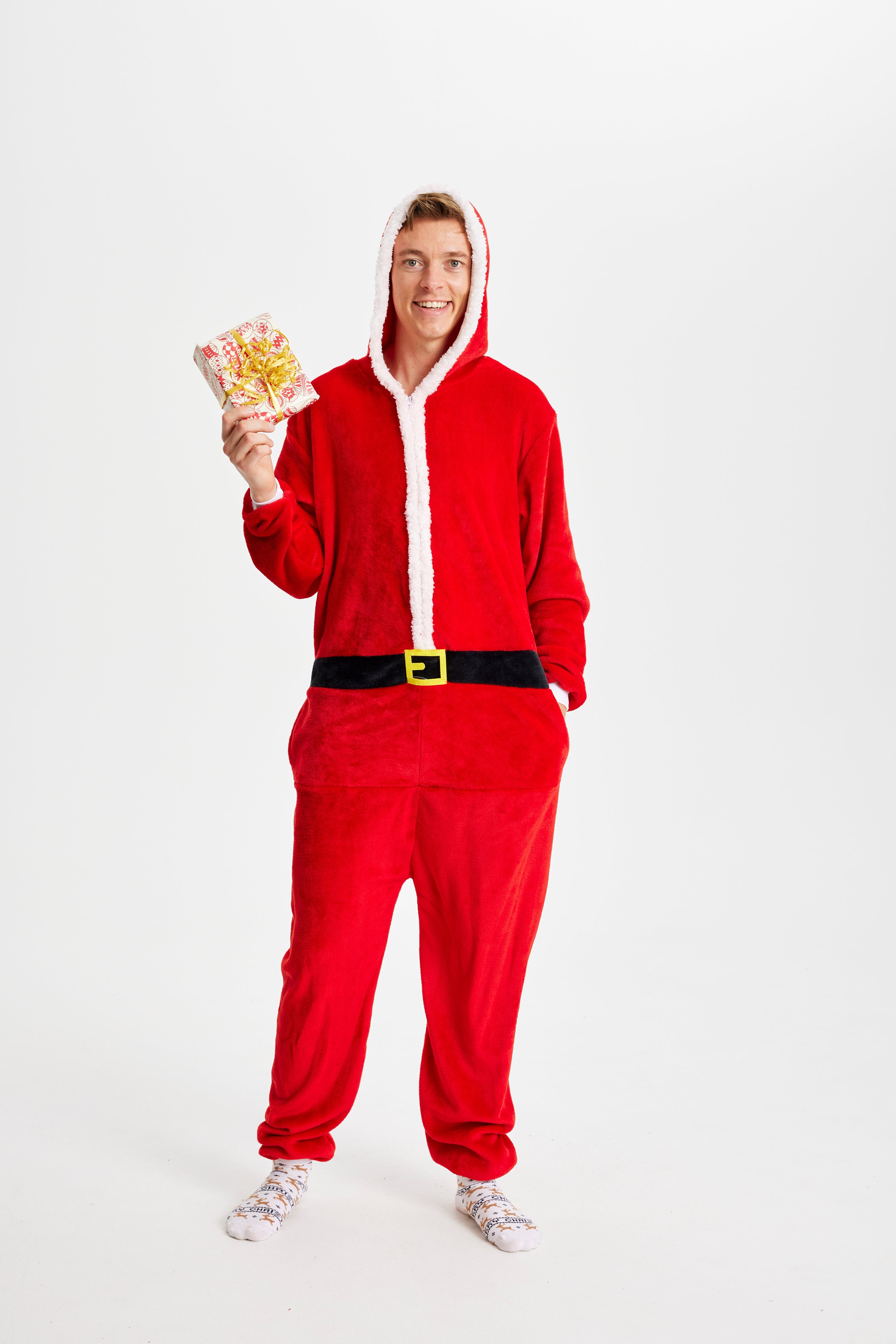En mand med en julegave i hånden står iført en rød jumpsuit.