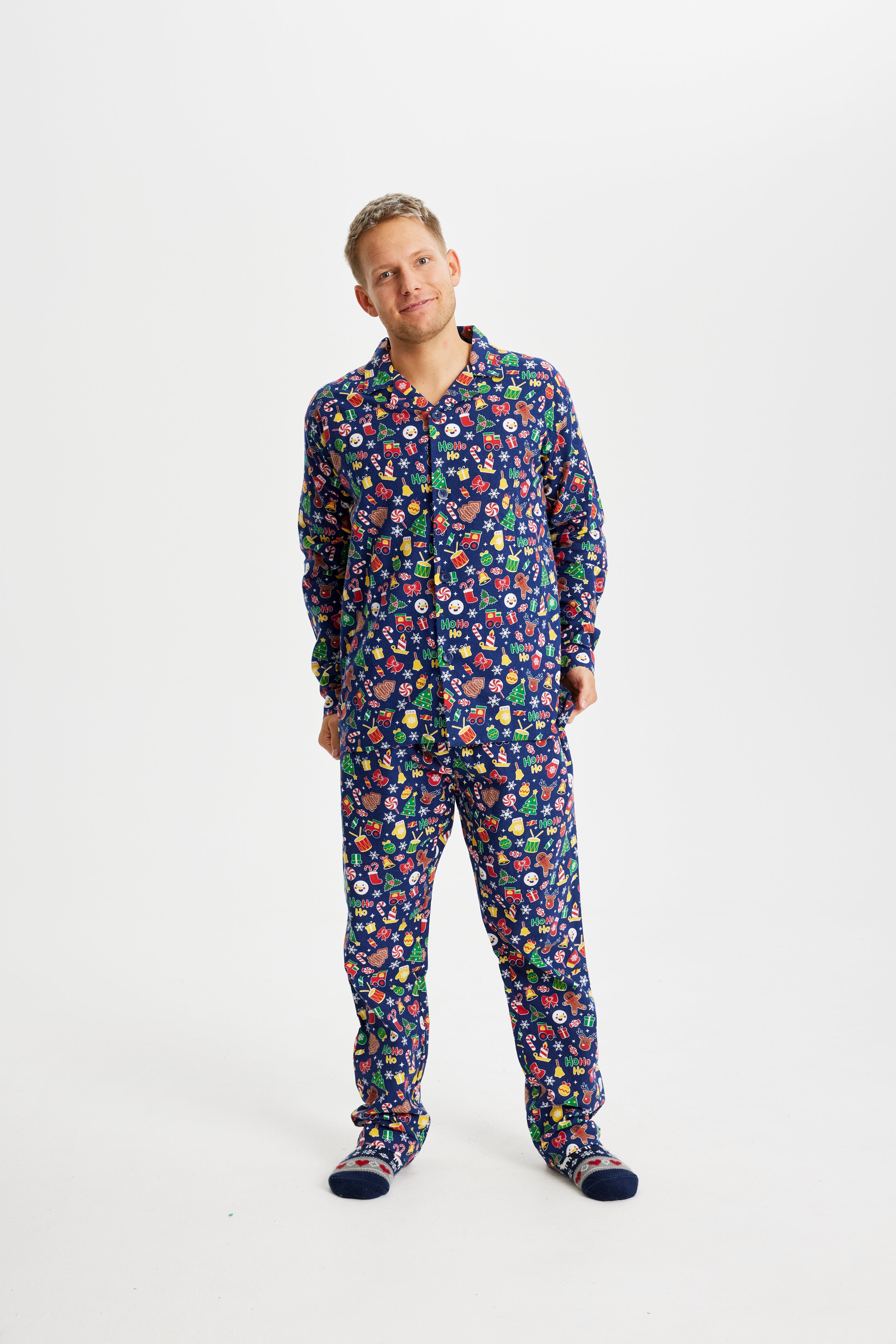 En smilende mand iført en julepyjamas med julepynt på.