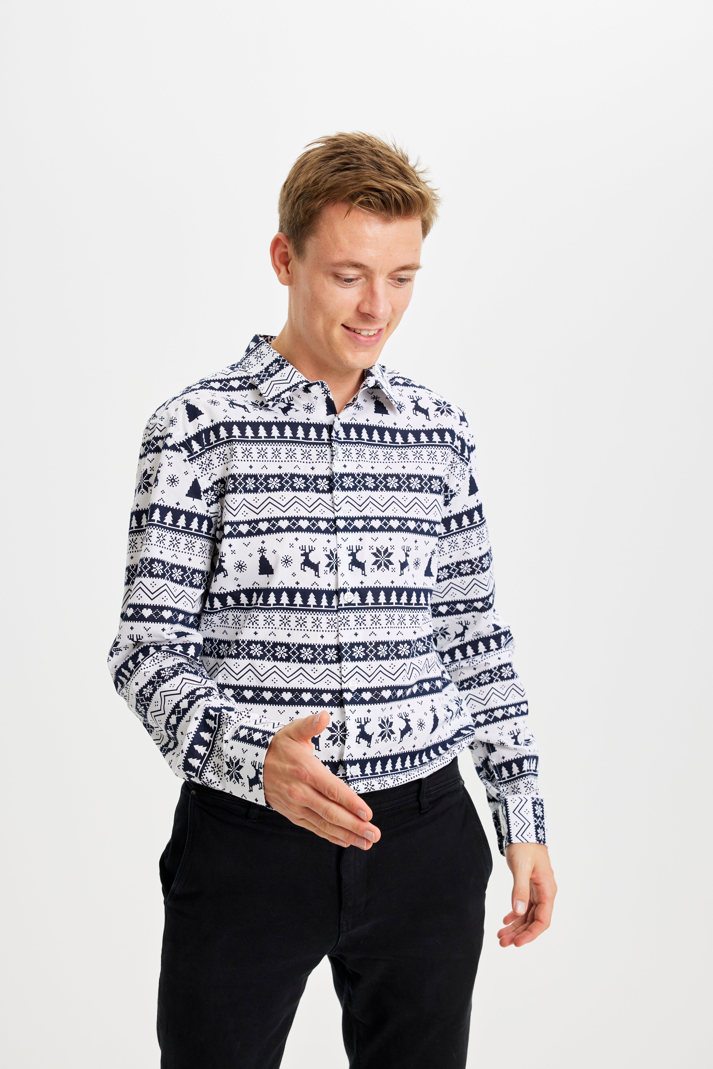 En smilende mand kigger ned og er iført en sort og hvid juleskjorte med mønster på.