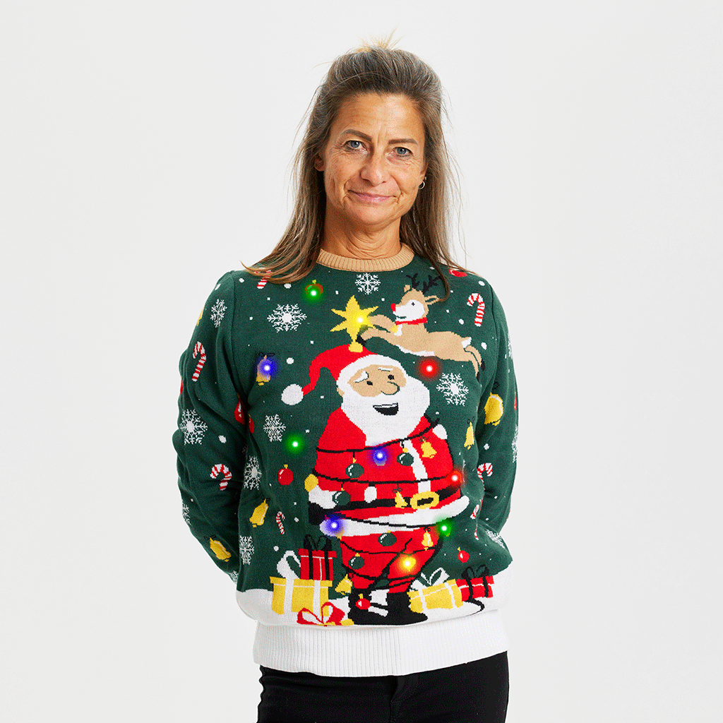 En kvinde iført en grøn julesweater med lys og snefnug på.