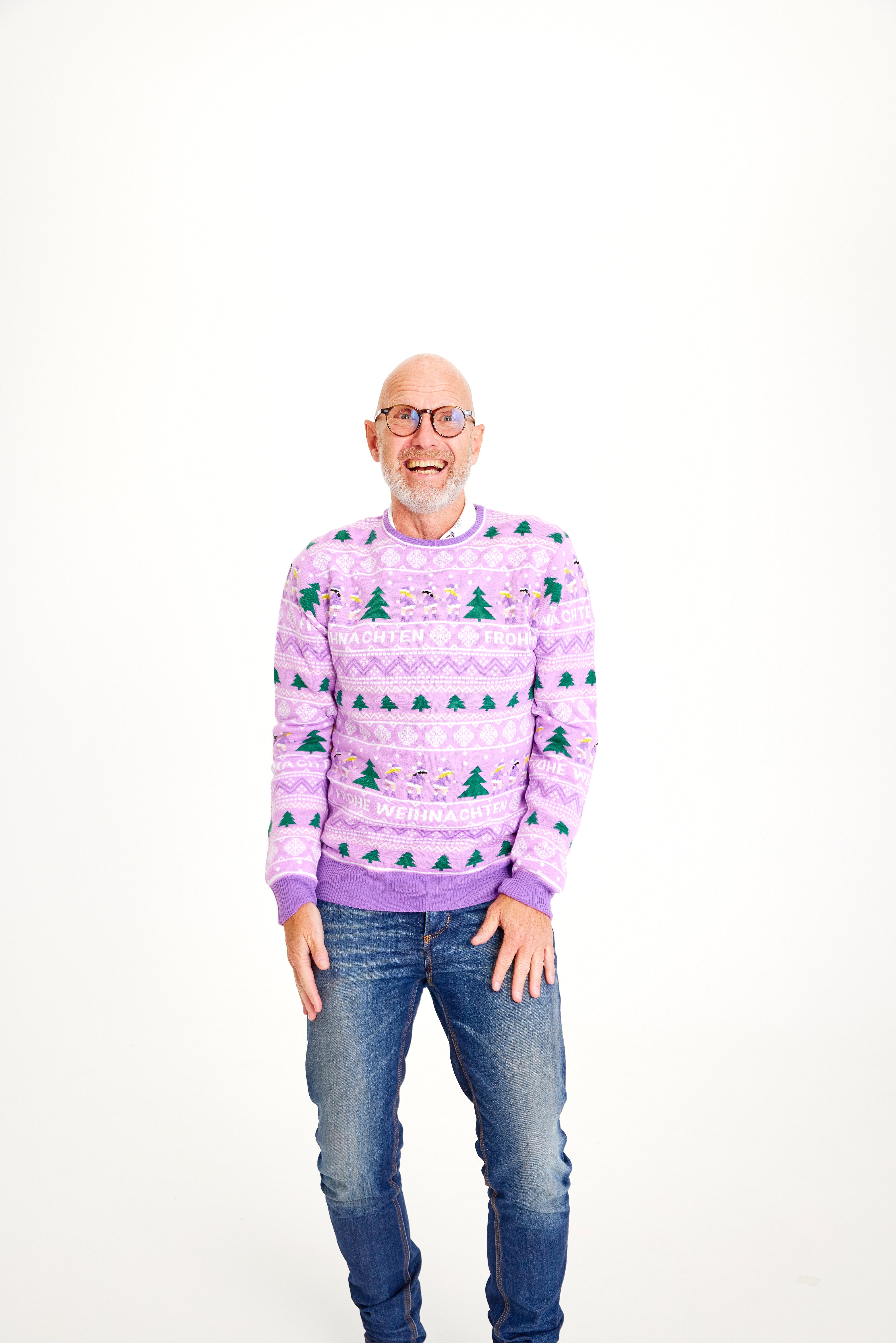 En smilende mand i en lilla julesweater.