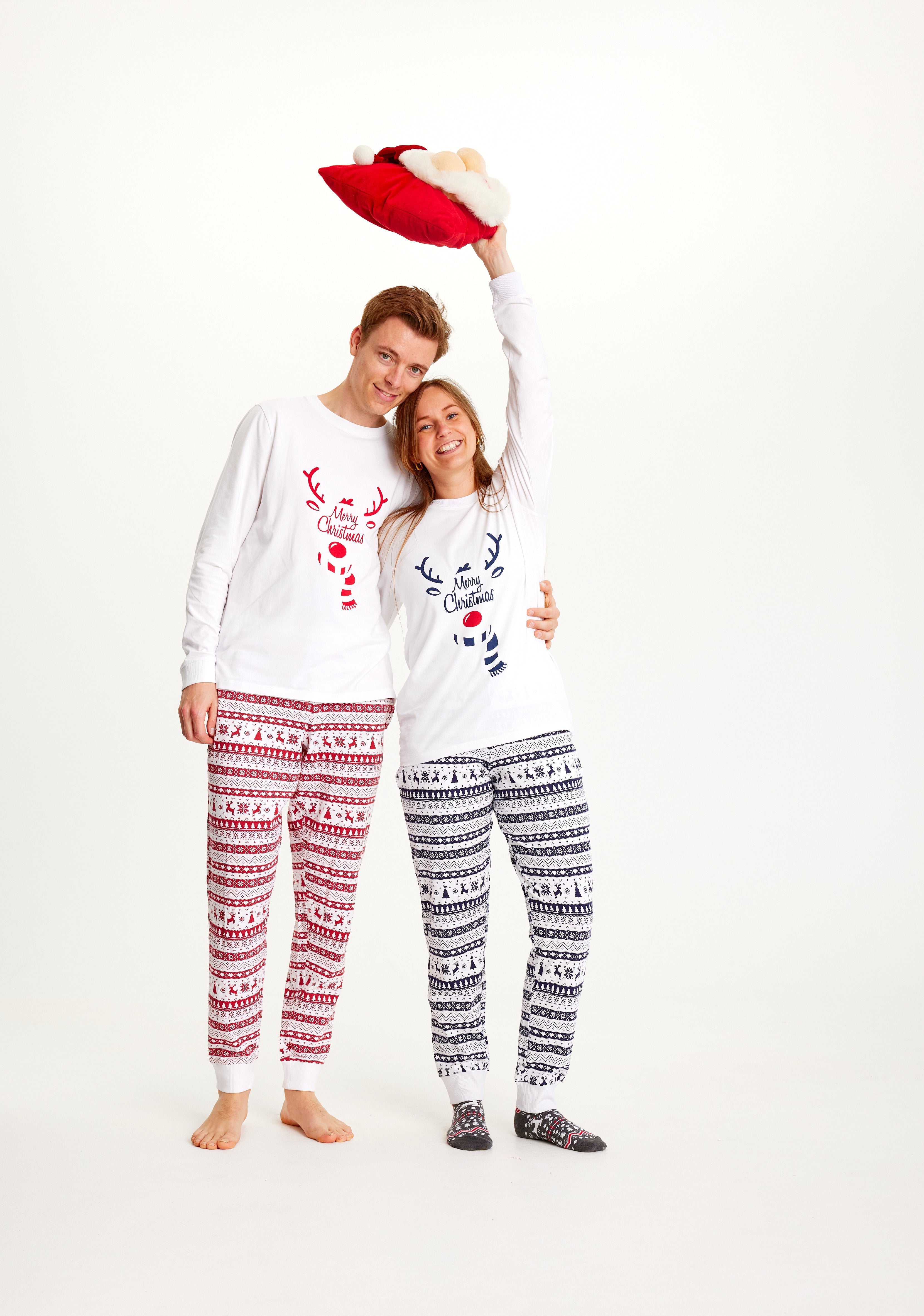 En mand og en kvinde poserer i deres hvide julepyjamas.