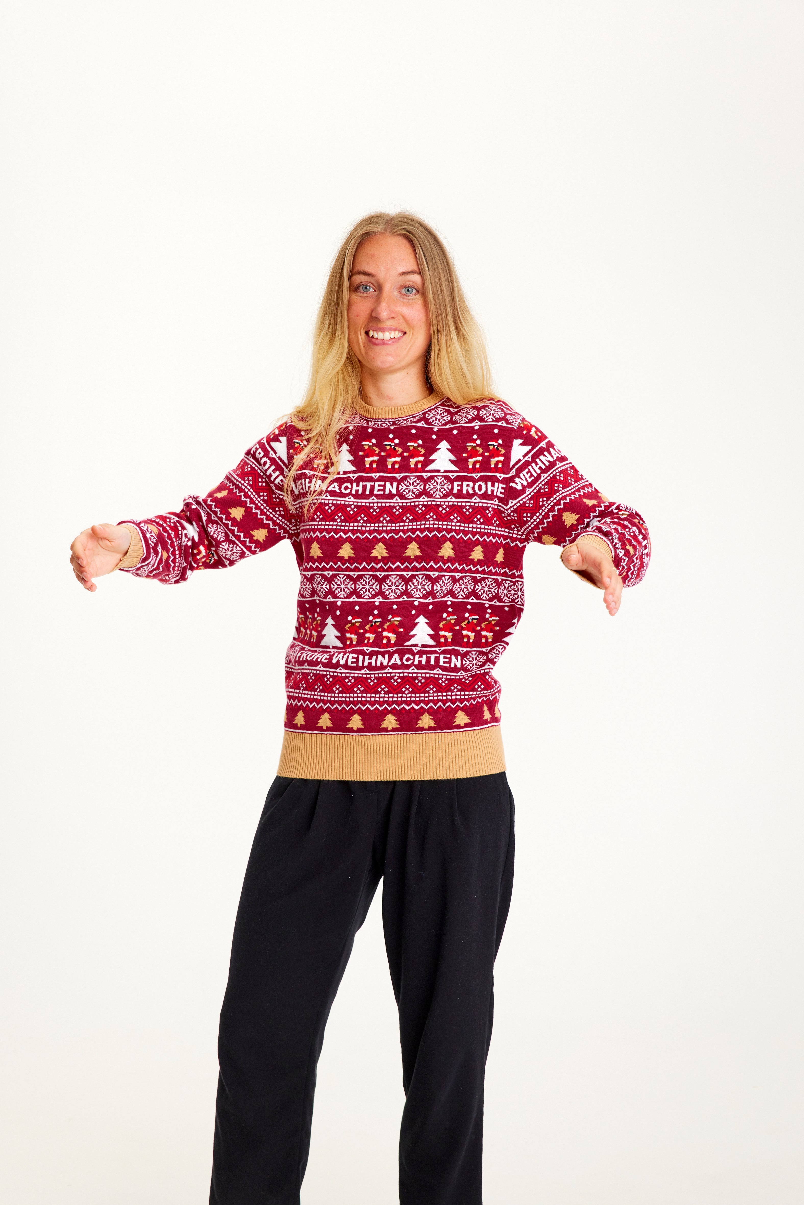 En smilende dame iført en rød julesweater med mønster.