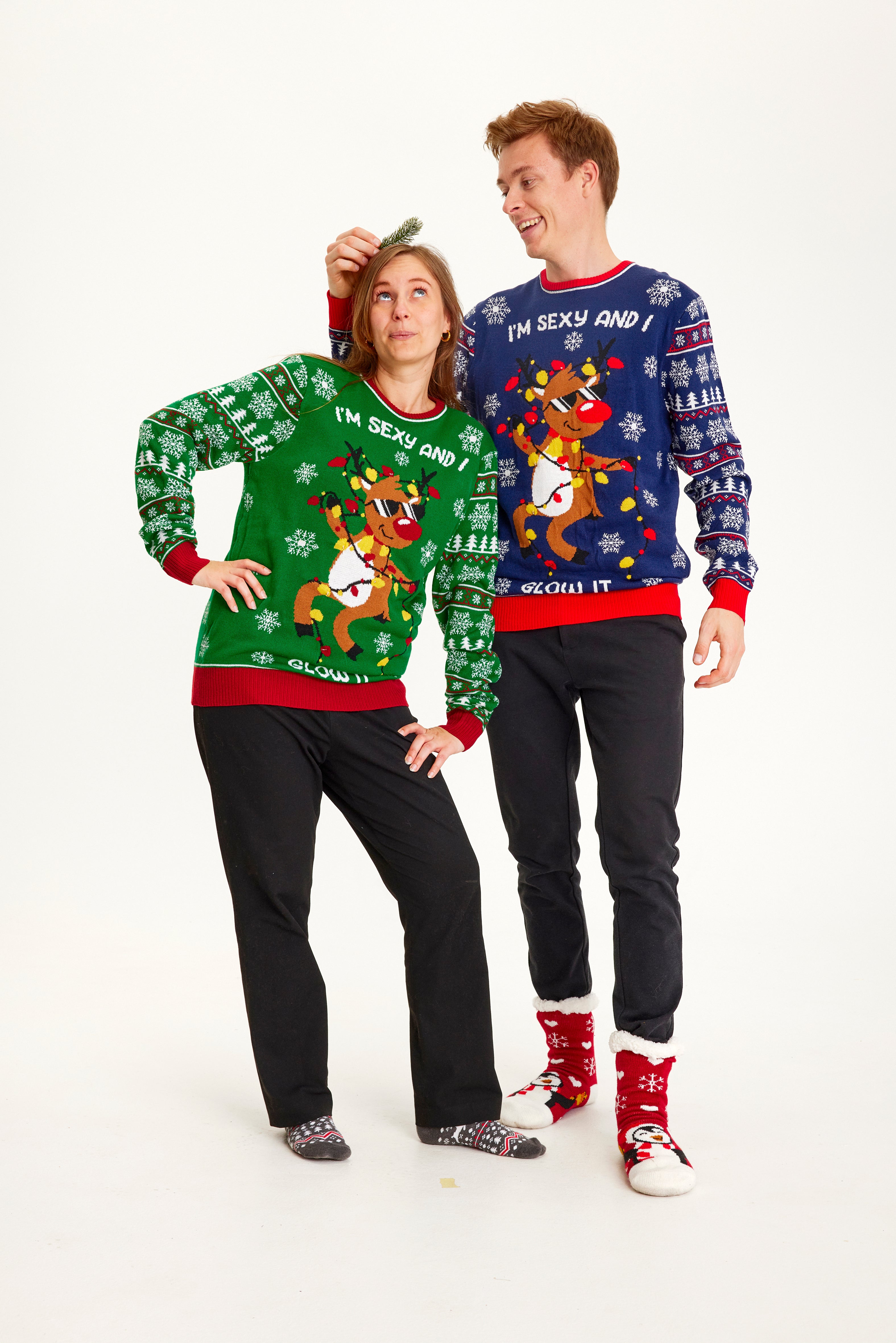 En mand og en kvinde poserer sammen, mens der er iført hver deres julesweater.